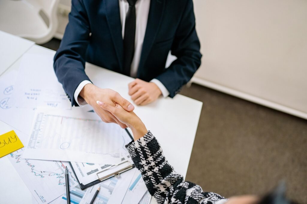 pexels-photo-7693160-7693160 Two professionals formalizing a business agreement with a handshake over a desk.
